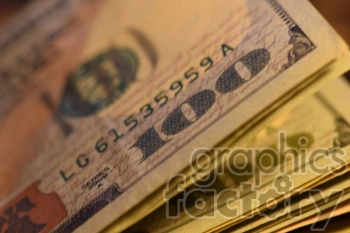 The photo shows a stack of US dollar bills, with the top bill facing forward and the rest of the bills visible behind it.
