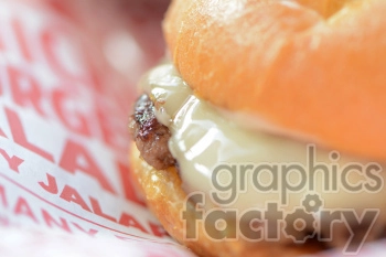 The photo shows a cheeseburger, likely prepared for lunch. It consists of a grilled beef patty, topped with melted cheese and served on a sesame seed bun. The burger may also include lettuce, tomato, pickles, onions, ketchup, mustard, and mayonnaise, although these additional components are not visible in the photo.
