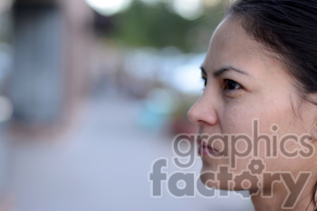 A close-up profile of a woman looking intently at something in the distance, with an urban background out of focus.