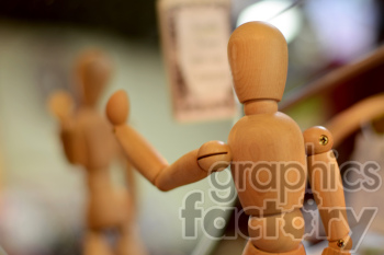 A close-up photograph of a wooden mannequin figure posing in front of a mirror, showing both its front and back sides.