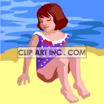 A girl in a blue and white polka dotted bathing suit sitting on the beach