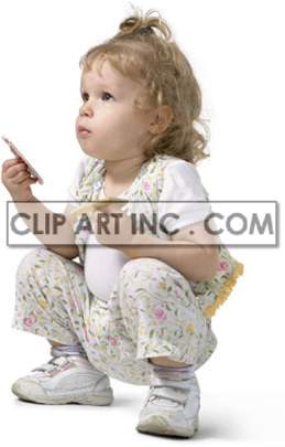 A young child with curly blonde hair, wearing a floral outfit, is squatting down holding a snack or a toy in one hand and a piece of paper in the other.
