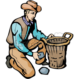 A cowboy in traditional Western attire kneeling on the ground, placing rocks into a basket.