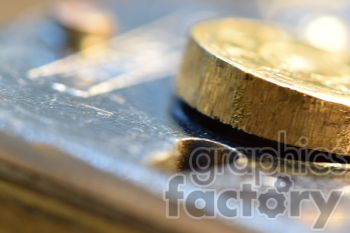 A close-up macro photograph of a metallic surface with a round golden knob or coin-like object.