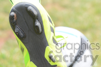 Close-up of a neon green soccer cleat with a soccer ball in the background on a grassy field.