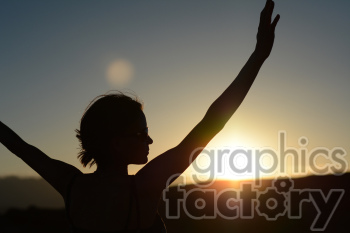 Silhouette of a person with arms raised against a sunset background.