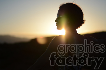 Silhouette of a person wearing sunglasses against a setting sun