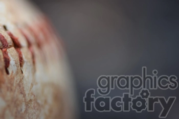 An extreme close-up of a worn baseball showing the red stitches and textured surface.