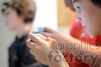 This image shows three children focused on their handheld electronic devices. They appear to be playing games or using applications.