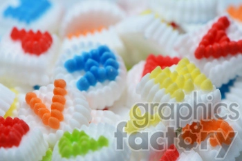 This clipart image shows a close-up of colorful sugar candies with different shapes and patterns. The candies are predominantly white with raised, multicolored designs in hues of red, blue, yellow, orange, and green.