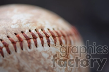 Close-up image of a worn baseball with visible red stitching.