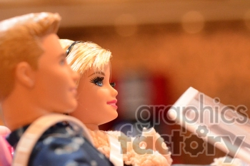 Close-up image of two dolls sitting side by side with one holding a plastic sheet.