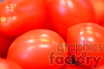 A close-up image of several red tomatoes featuring smooth and shiny surfaces, emphasizing their fresh and ripe appearance.