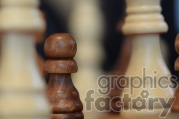 Close-up of wooden chess pieces, with a pawn in the foreground and other pieces out of focus in the background.