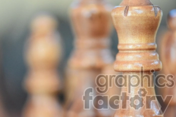Close-up of wooden chess pieces, focusing on the king in a blurred background.