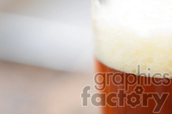 Close-up image of a glass filled with amber-colored beer, topped with frothy foam.