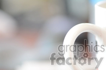This image features an unfocused and blurred background with a close-up view of a white coffee mug handle. The background consists of various colors blending into each other, giving a bokeh effect.