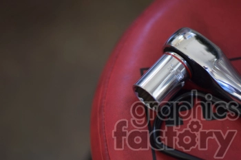 A close-up of a shiny socket wrench placed on a red surface with black text.