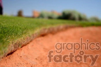 Close-up of the edge of a sand bunker and grass on a golf course.