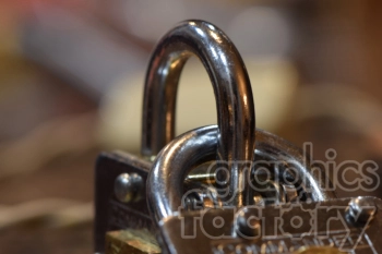 Close-up image of two shiny metal padlocks linked together with a blurred background.