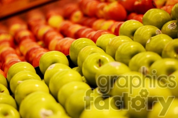 A vibrant display of green and red apples arranged in neat rows at a market or grocery store.