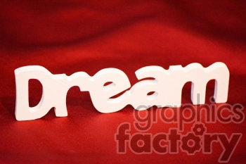 A white 3D cutout spelling the word 'Dream' on a rich red fabric background.