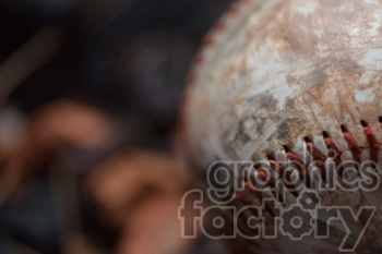 Close-up image of a dirty, worn baseball with red stitching.