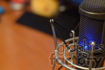 Close-up view of a studio microphone with metallic mesh and blue LED lights, mounted on a shock mount.