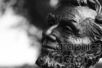A black and white image of a bronze bust sculpture, depicting a distinguished person with a beard. The background is blurred, directing focus on the detailed facial features of the sculpture.