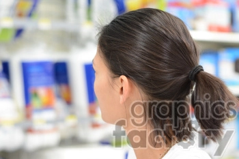 A person with dark hair tied in a ponytail is seen shopping in a store aisle, with shelves of products in the blurred background.
